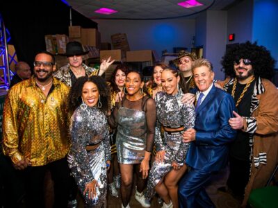 Group of performers in sparkly outfits smiling