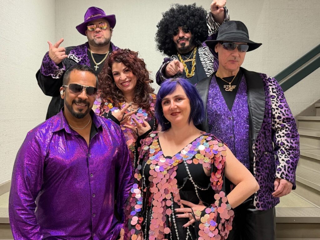 Group in purple disco costumes and sequins