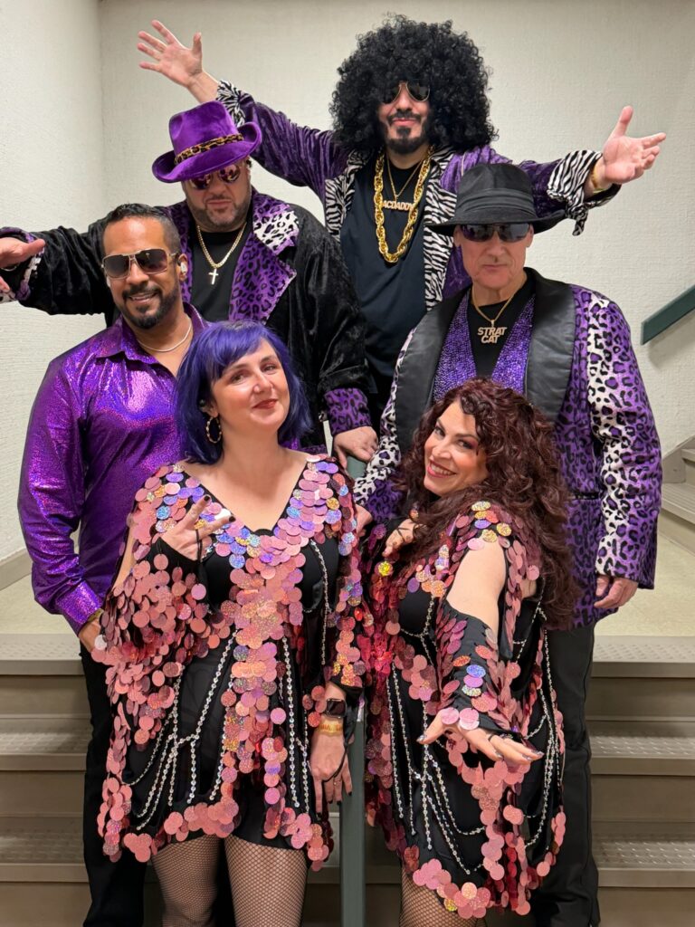 Group of performers in purple disco outfits